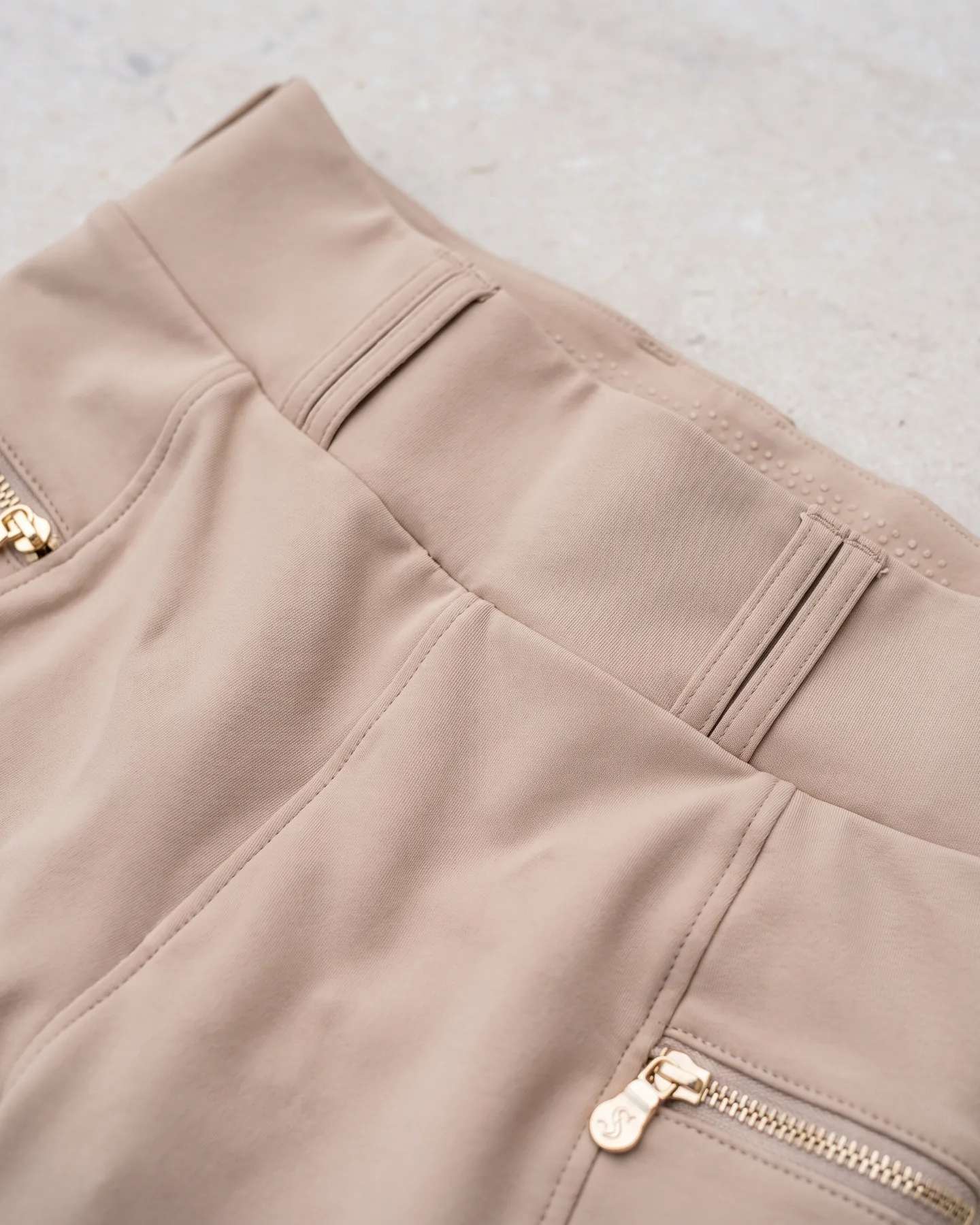 Ceinture haute d’un pantalon d’équitation beige, passants et surpiqûres