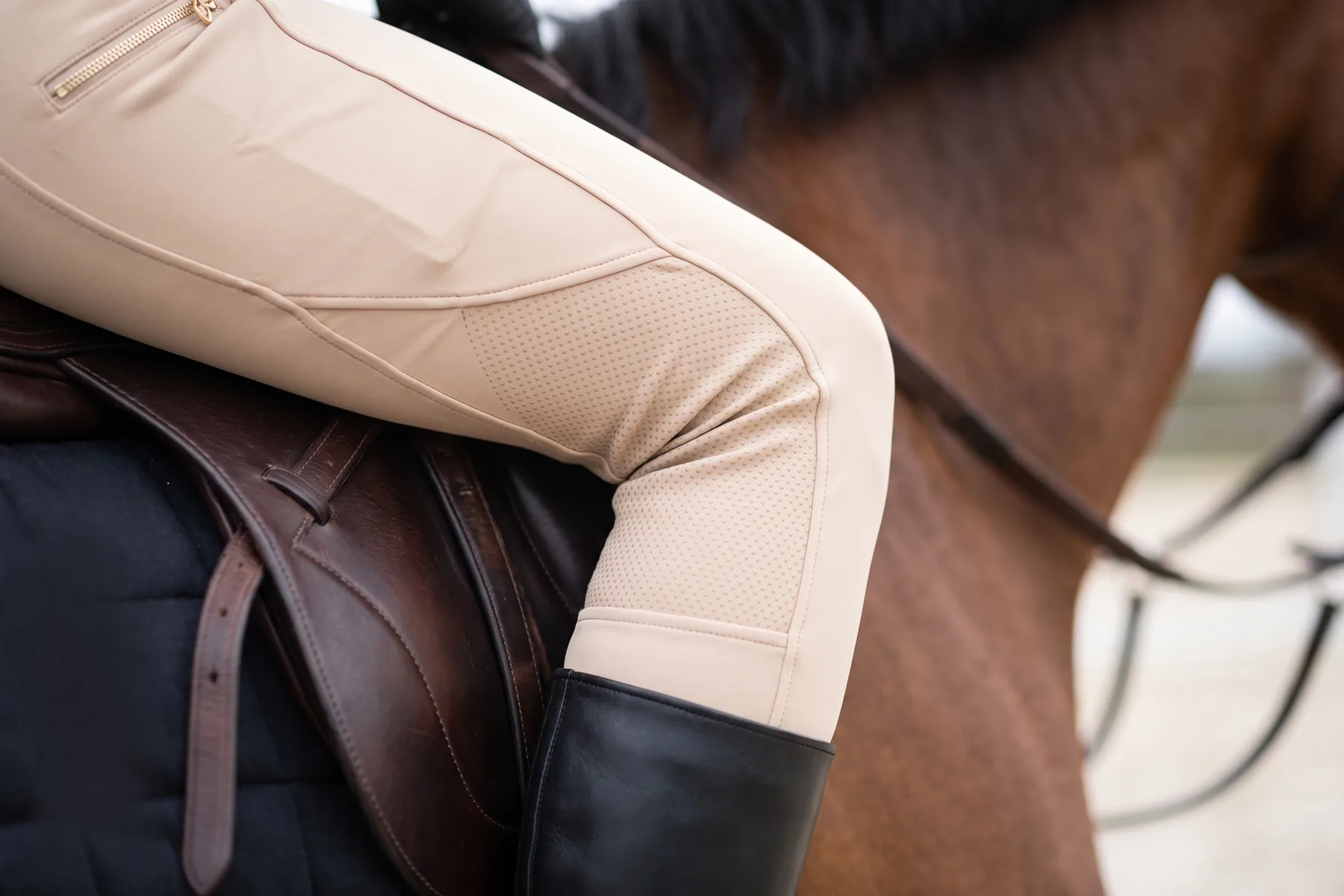 Grip silicone au genou d’un pantalon beige contre le quartier de la selle